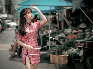 Asian woman in a pink modern qipao dress, combining classic elegance with modern charm.